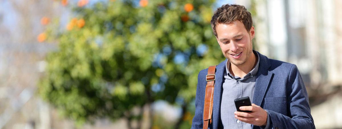 man happily looking at his phone as he walks