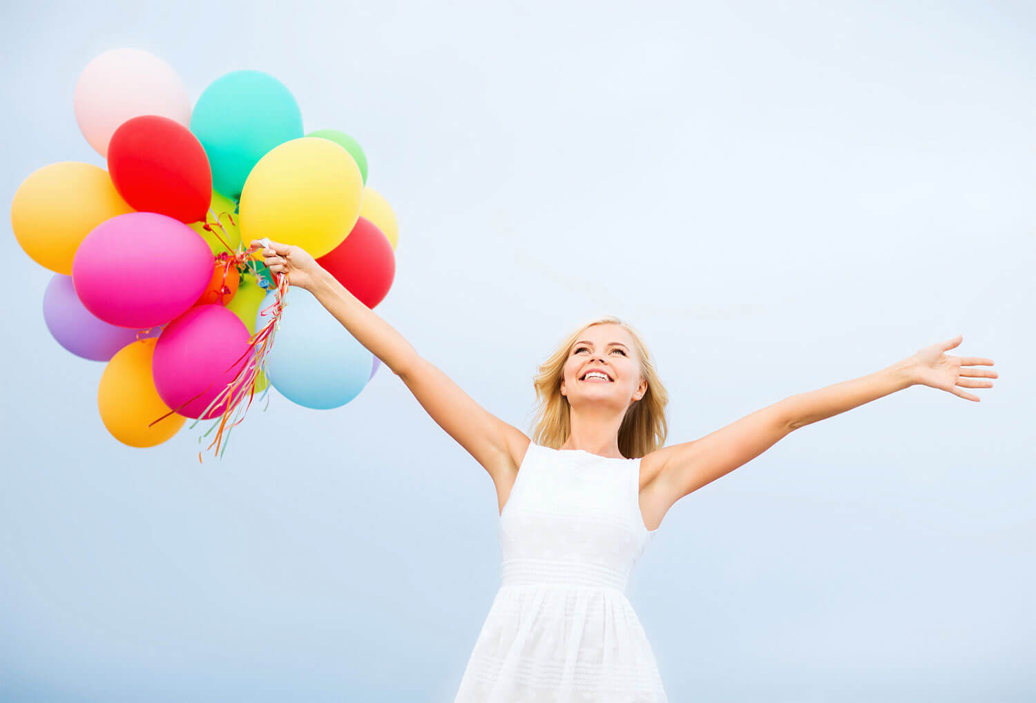 Women holding balloons in her hand while she looks happily into the sky