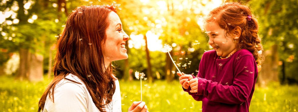 Mom and daughter blowing dandelion seeds