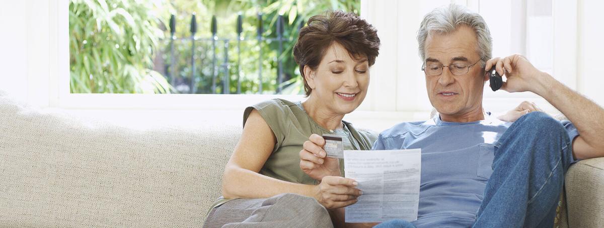 elderly couple sitting on the couch while the husband is on the phone