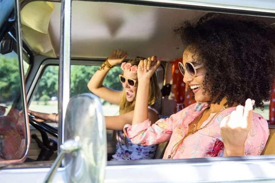 Two friends in a car are laughing and dancing