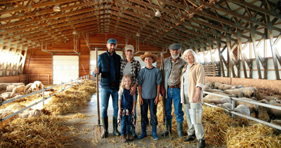 farm family posing in barn with hay and animals for photo