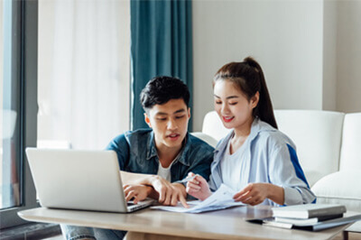 Young couple looking at papers in front of a laptop