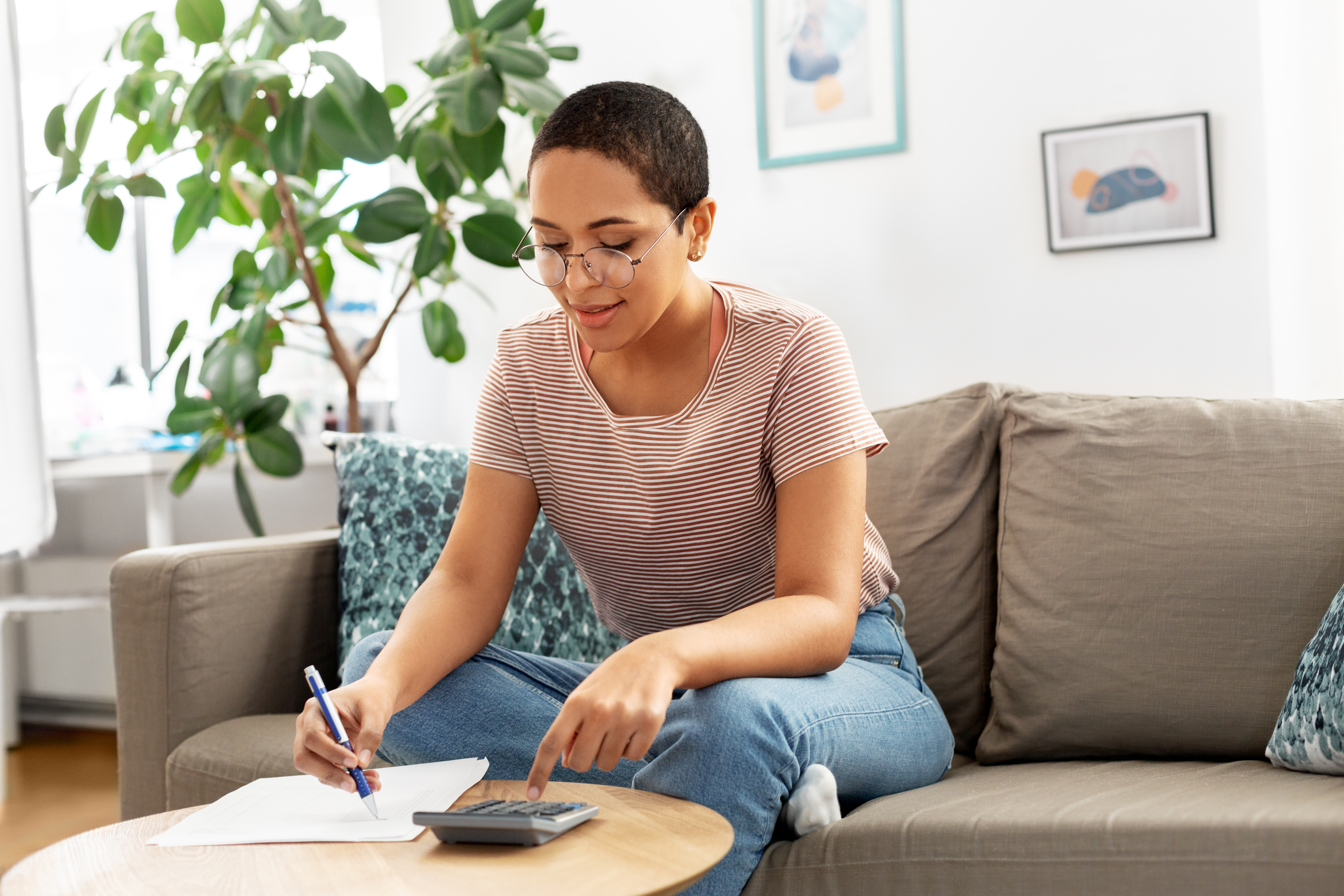 young african american woman in glasses with papers and calculator at home