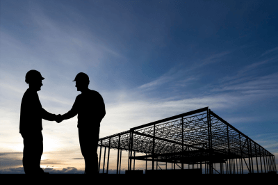 Two men shaking hands near a construction site