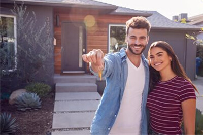 young couple holding keys outside of their new home