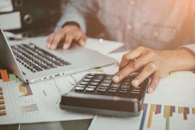 man making calculations on a calculator while also typing into a laptop