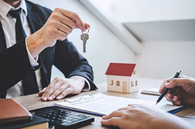 lender holding a key as borrower signs document