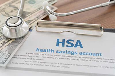 Image of paper that says HSA - Health Savings Account - a stethoscope and money