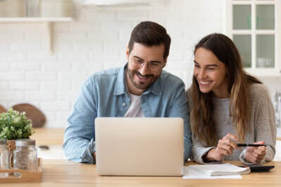 Young couple in their kitchen looking at a laptop