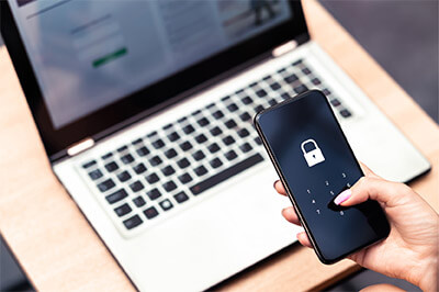 Hand holding a locked phone over a laptop