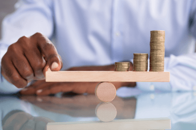 Business measuring the weight of his coins on a scale to find a balance