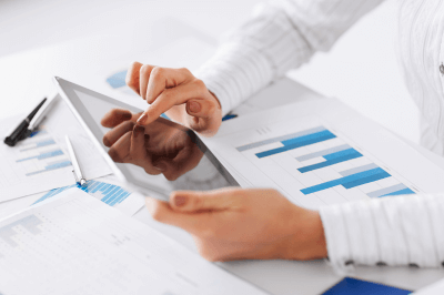 Business owner looking at a tablet with pictures of graphs on the table
