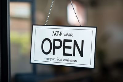 Sign on a door that says: Now we are Open - Support local businesses-