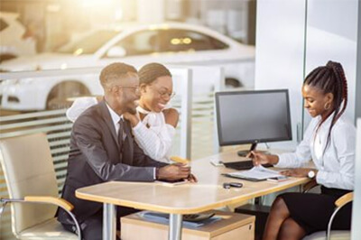 Couple meeting with a lender at a car dealership