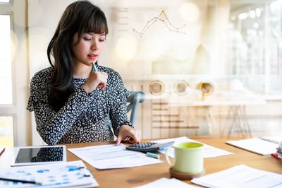 young woman looking at a calculator and paperwork