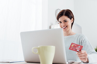 Woman looking at a laptop screen holding her debit card