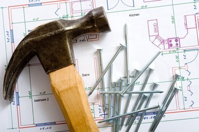 close up of a hammer and nails on top of blueprints 