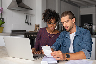 Couple looking at their laptop and paperwork at their kitchen table