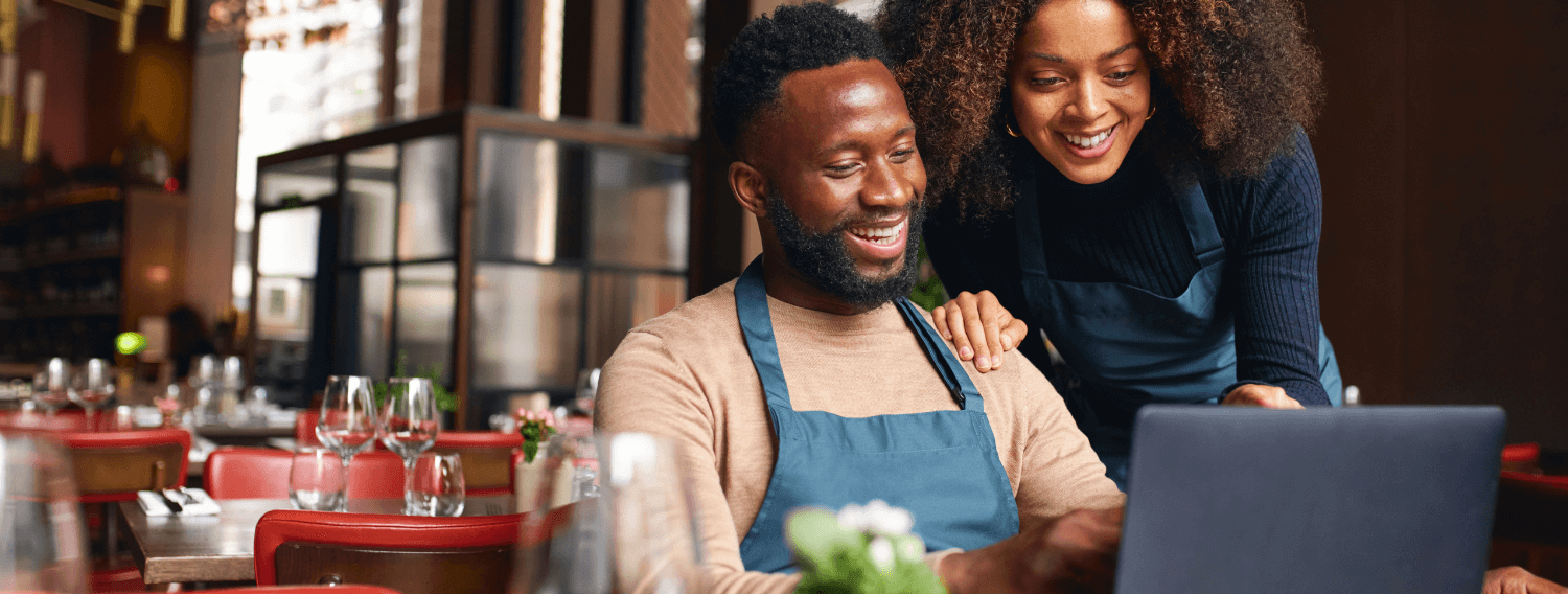 Business owners looking at a laptop while they smile