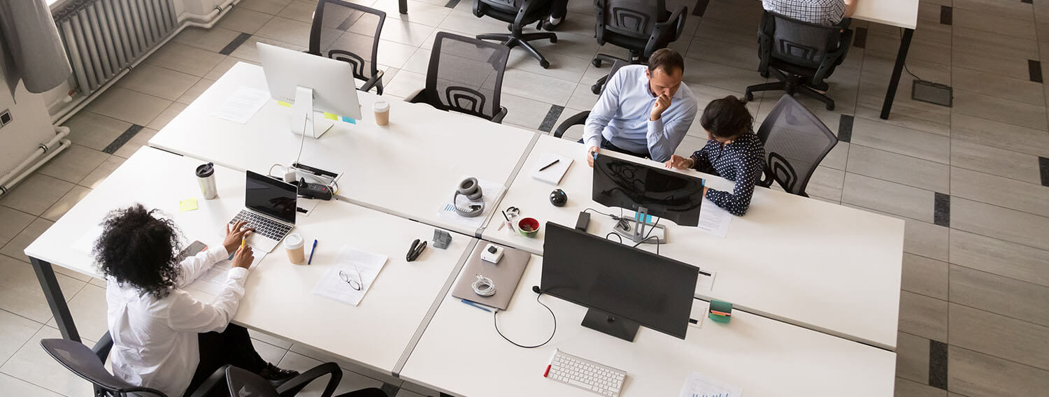 aerial view of workers sitting at desks in an open concept office