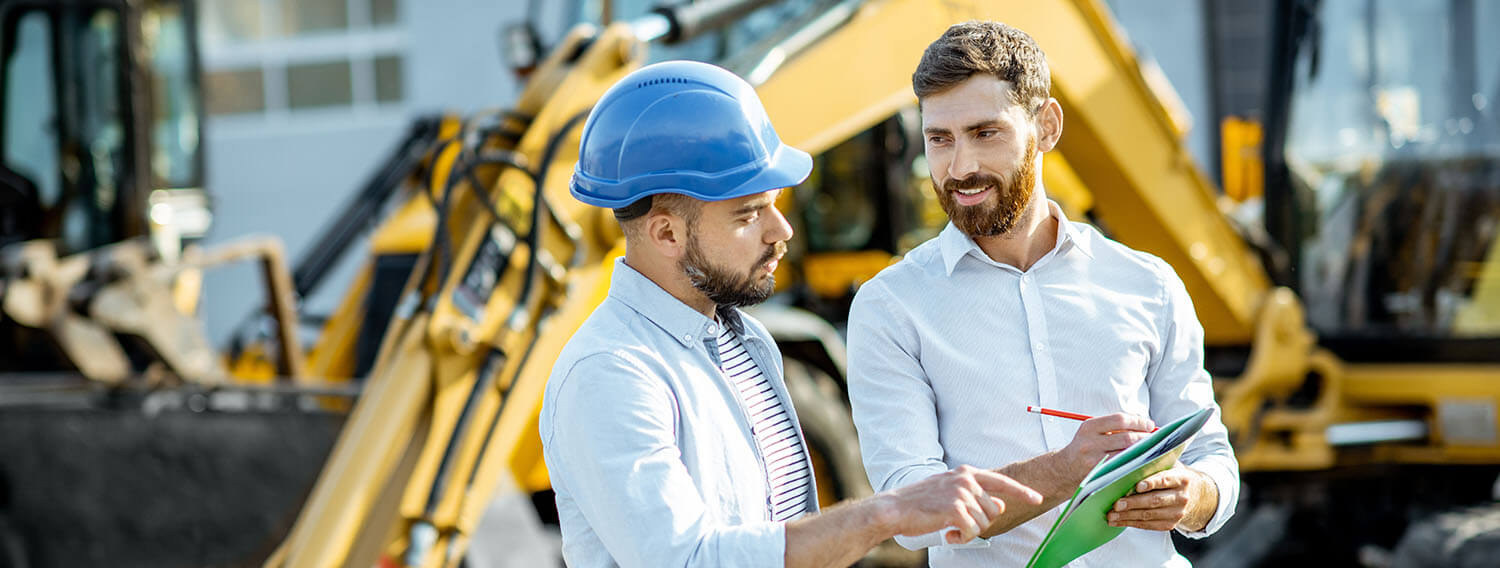 professionally dressed men at a construction site looking at paperwork