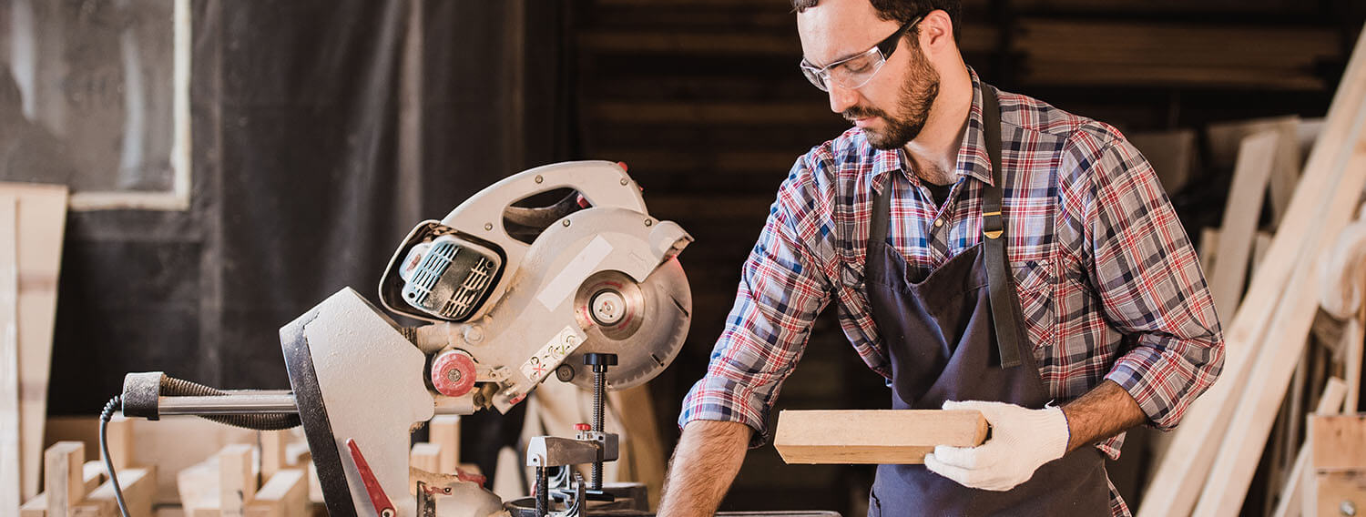 Carpenter cutting wood with sawing equipment