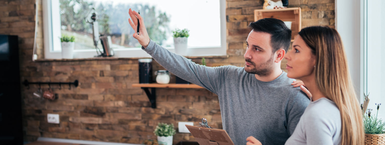 Couple looking around their home with a clipboard trying to envision renovations