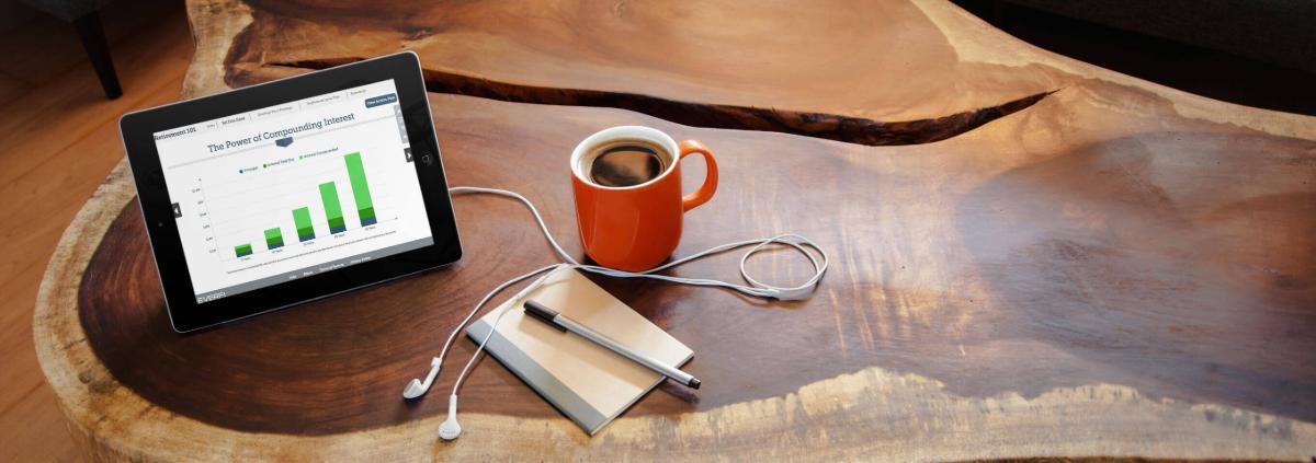 Cup of coffee next to some headphones and an iPad displaying a bar graph