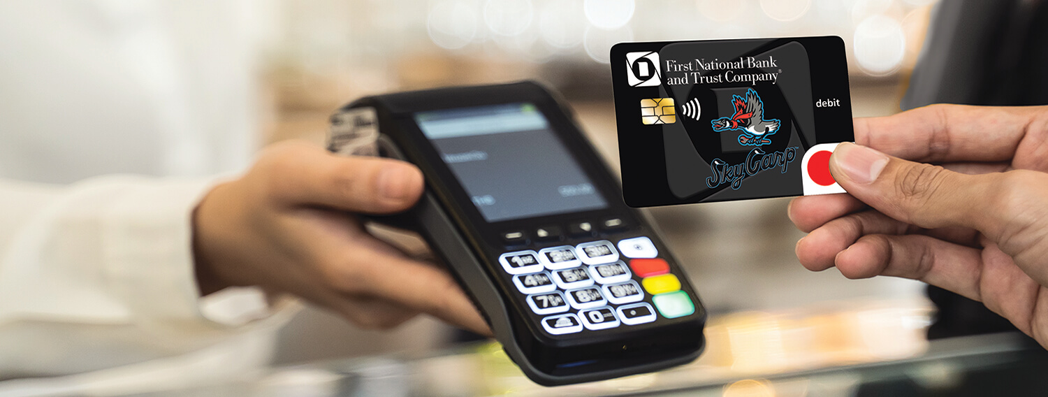 Hand using the exclusive contactless FNBT Sky Carp debit Mastercard to pay