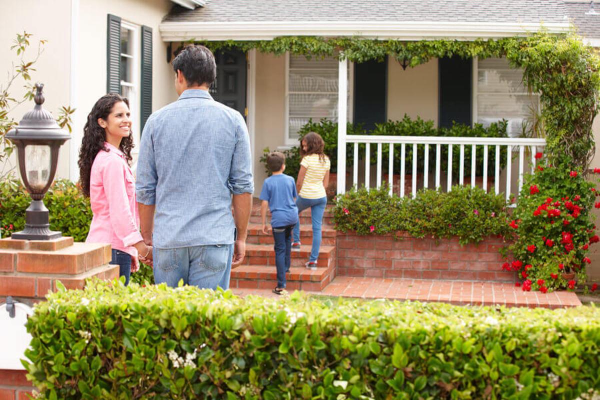 Happy family of four are standing outside their home