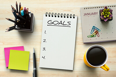 Note pad on a desk that reads 'Goals followed by a blank list 