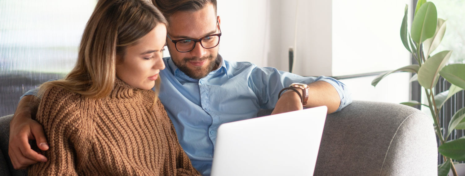 Couple sitting on the couch looking at a laptop