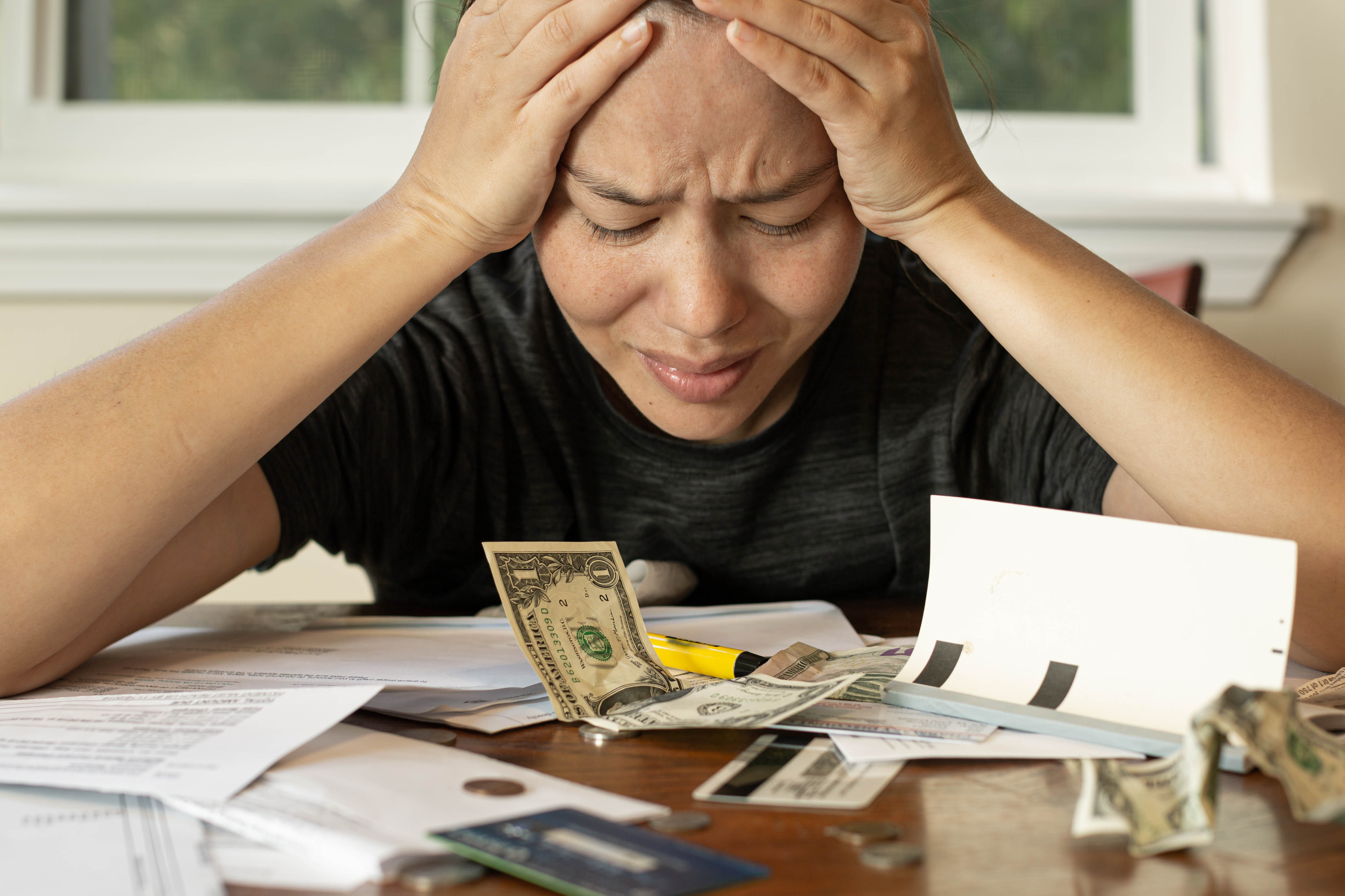 Woman looking at her financial bills stressed out with her head in her hands