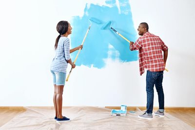 father and daughter painting a wall in home
