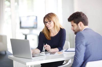 young man in suite with woman looking at her laptop