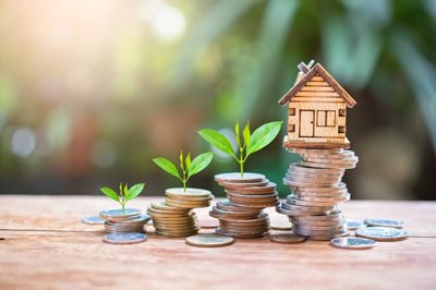 small model of a house on top of a pile of coins