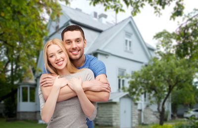 young couple hugging in front of home
