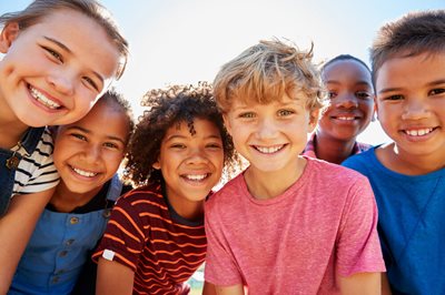 diverse group of small kids huddled and smiling