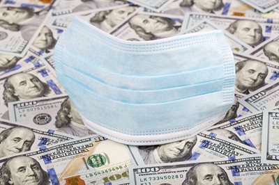 covid mask on top of money bills spread out