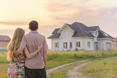 young couple hugging staring at new home from a distance