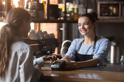 Woman making a purchase with her smart phone in a small coffee shop