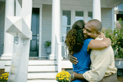 couple hugging in front of house